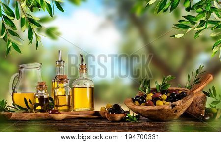 Freshly harvested olives berries in wood bowls and pressed oil in glass bottles. Still life of food preparation served on old wooden planks. Free space for text