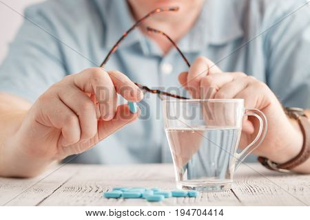 Male Hand Holding Blue Pill Between Fingers