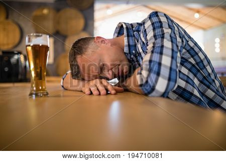 Drunken man sleeping on counter in bar