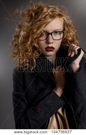 Beautiful red-haired girl with glasses and a dark coat