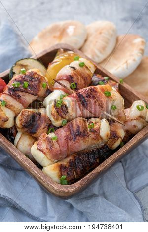 Grilled bacon wrapped haloumi cheese with vegetables and pita