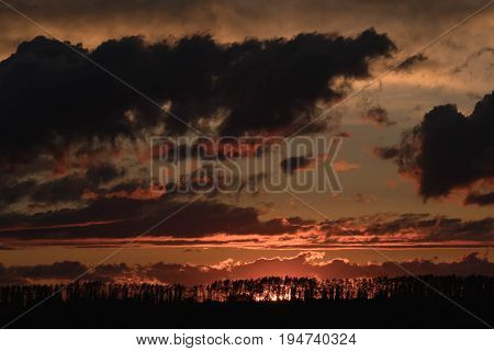 Sunset against the background of the evening sky with colorful shades of flowers on the clouds
