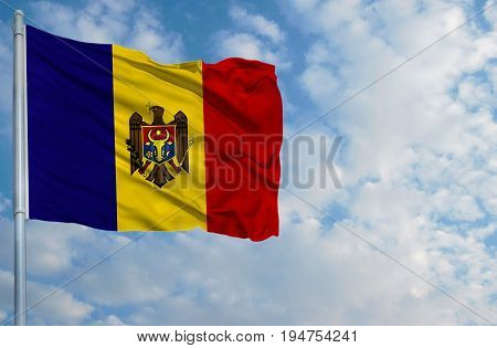National flag of Moldova on a flagpole in front of blue sky.