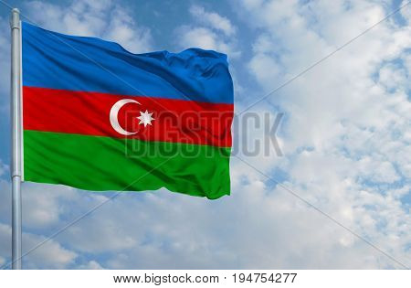 National flag of Azerbaijan on a flagpole in front of blue sky.