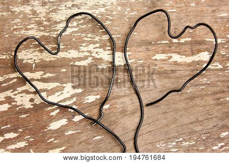 Wire bent in shape of two heart togather on wooden background