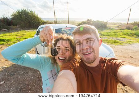 Young funny couple with keys to new car outdoor.