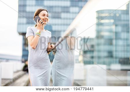 Lifestyle portrait of a business woman dressed casually standing with phone on the modern bridge in Dusseldorf city, Germany