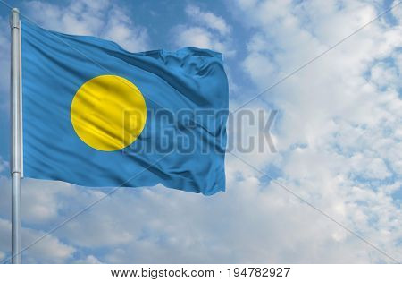 National flag of Palau on a flagpole in front of blue sky.