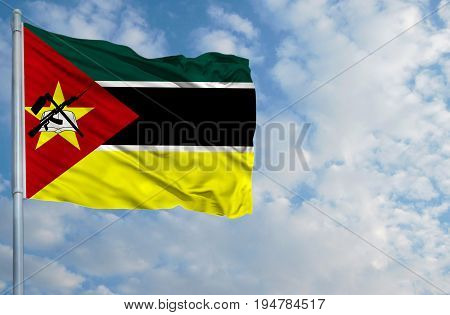 National flag of Mozambique on a flagpole in front of blue sky.