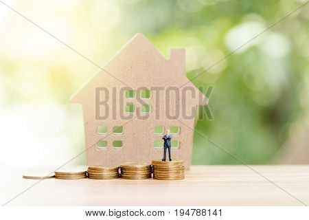 Miniature People,real Estate Investment. House And Coins On Table.