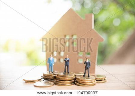 Miniature People,real Estate Investment. House And Coins On Table.