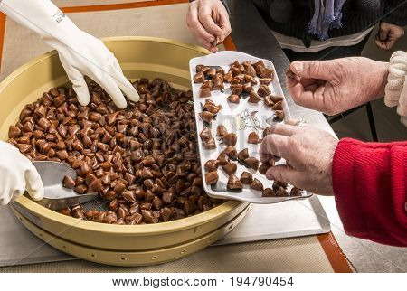 Artisanal production of caramel toffee sweets butterscotch candies. Woman with white gloves shaking put in jar get in the jugs the pieces of butterscotch candies traditional sweets of France