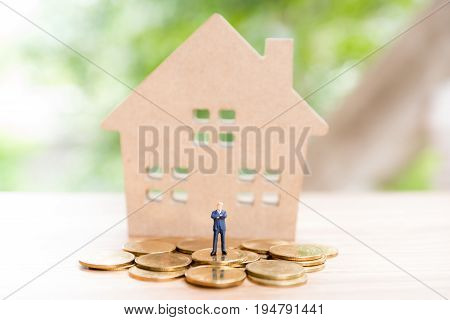 Miniature People,real Estate Investment. House And Coins On Table.