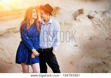 An Attractive Man Hugs A Beautiful Woman In A Blue Dress In The Middle Of A Sandy Canyon. Lovers Are