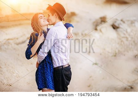 An Attractive Man Is Hugging And Kissing An Beautiful Woman In A Blue Dress In The Middle Of A Sandy