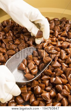Artisanal production of caramel toffee sweets butterscotch candies. Woman with white gloves shaking put in jar get in the jugs the pieces of butterscotch candies traditional sweets of France