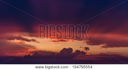 Rays of sun light coming through hole in purple storm clouds