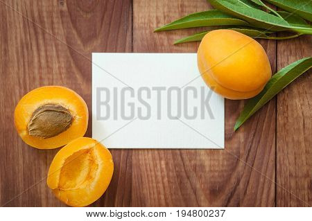 Ripe apricots and blank card for inscription on a wooden table. close up of fresh apricots on a wooden table