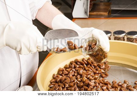 Artisanal production of caramel toffee sweets butterscotch candies. Woman with white gloves shaking put in jar get in the jugs the pieces of butterscotch candies traditional sweets of France