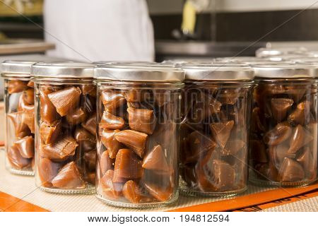 Artisanal production of caramel toffee sweets butterscotch candies. The pieces of butterscotch candies in jars jugs ready for saling traditional sweets of France