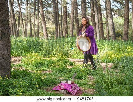 Female shaman drumming and chanting with altar
