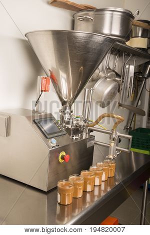 Automated food factory machine get the caramel jam in the jugs. Close up