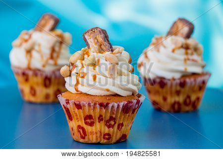 Three Caramel nut cupcakes isolated on blue background