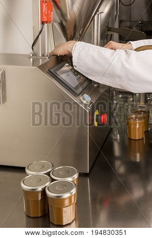 Automated food factory machine get the caramel jam in the jugs. Close up