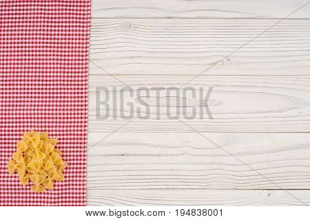 Pasta on kitchen napkin and an old white wooden table. Top view.