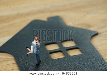 Miniature happy family figure standing on paper house as property or financial investment mortgage plan concept.