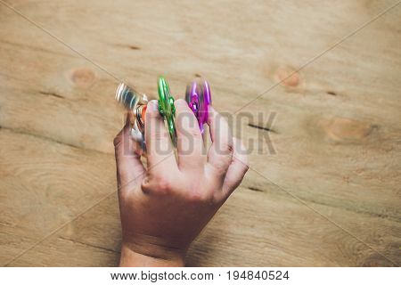 A Man Hand Holding Hand Spinner Or Fidget Spinner Over Wooden Background