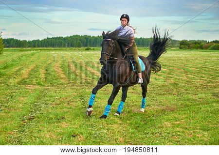 Pretty young girl riding a horse across country
