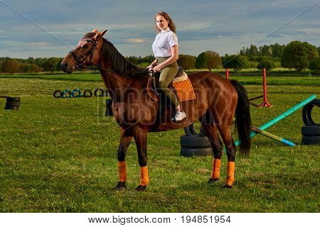 Pretty young girl riding a horse across country