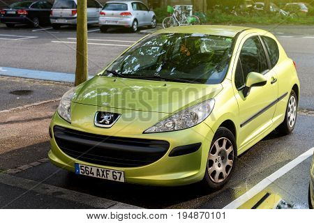 STRASBOURG FRANCE - MAY 30 2017: Lion logotype of in front of a green Peugeot 206 city car parked on the street. Peugeot is one of the bigest car manufacturer in the world