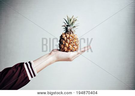 Isolated mockup hand holds a little pineapple on palm on white wall background simple and cute fruit setting