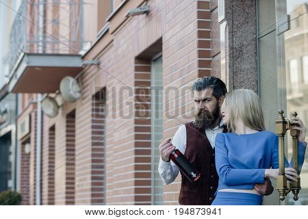 Hipster With Bottle Hugging Girl Standing At Glass Door