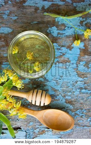linden honey and linden flowers on blue wooden table . . jar of linden honey. Photo with copy space