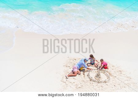Family making sand castle at tropical white beach