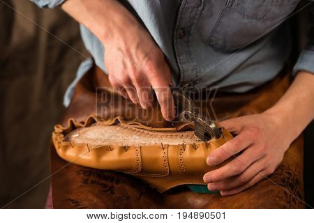 Cropped image of bootmaker sitting in workshop making shoes