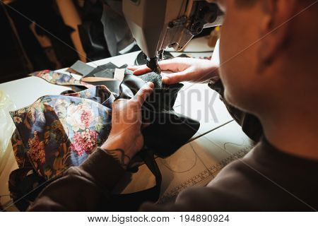 Cropped photo of young man shoemaker at footwear workshop.