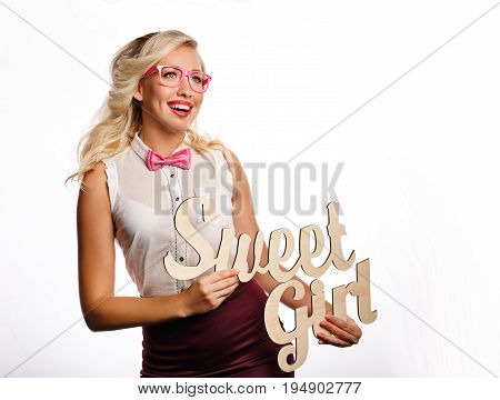 Young attractive girl holding an inscription of a sweet girl. She is wearing a blouse a bow tie and glasses.