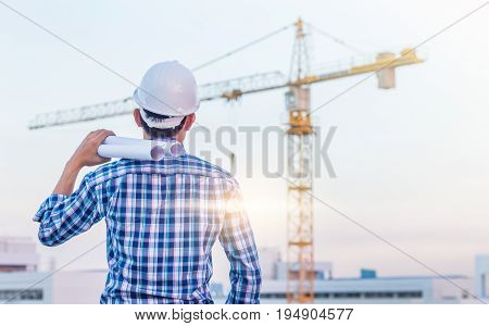 Portrait of architect wear white helmet safty hold the blueprint on construction site with crane background