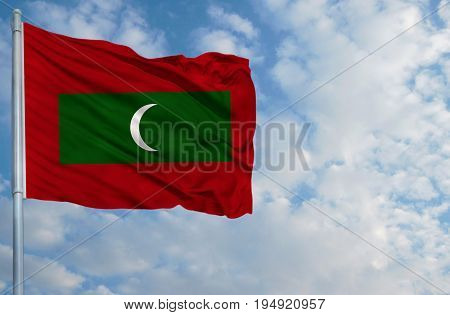 National flag of Maldives on a flagpole in front of blue sky.
