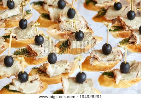 Catering of canape with olives baguette and meat on white background