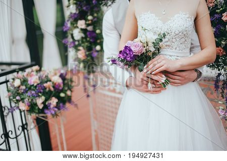 Stylish beautiful bride holds a wedding bouquet in hands