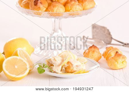 Lemon Profiteroles with custard cream on white dish.