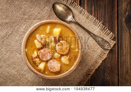 Wooden Bowl Of Split Pea Soup With Sausage And Potatoes