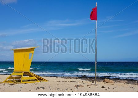 Yellow lifeguard tower. One life guard together with red flag on beach. Point of safe, surviving. Coastal view.