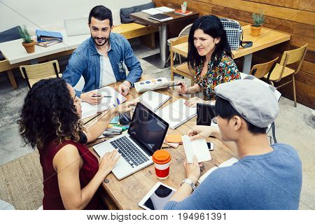 Startup of four multiethnic people discussing joyfully ideas in a modern coworking espace
