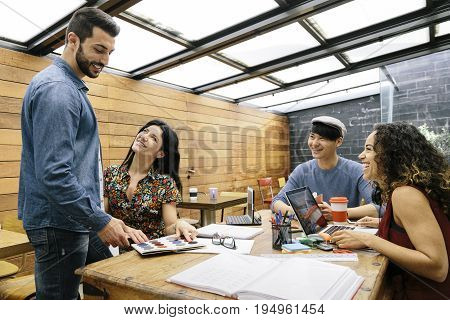 Startup of four multiethnic people discussing joyfully ideas in a modern coworking espace